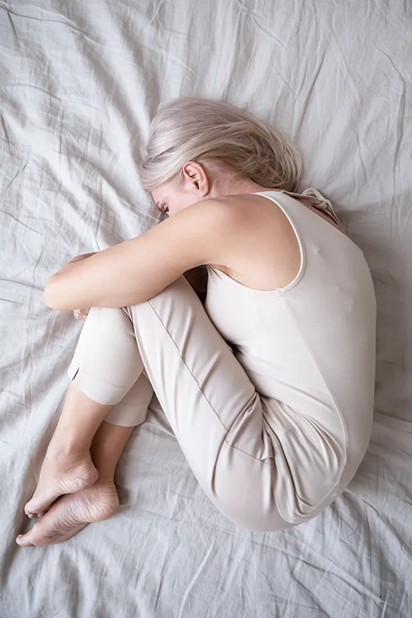 Anxiety-Treatment A woman curled up in the fetal position on her bed. Get anxiety treatment from Jennifer Jose-Cappola, MD in Stamford.
