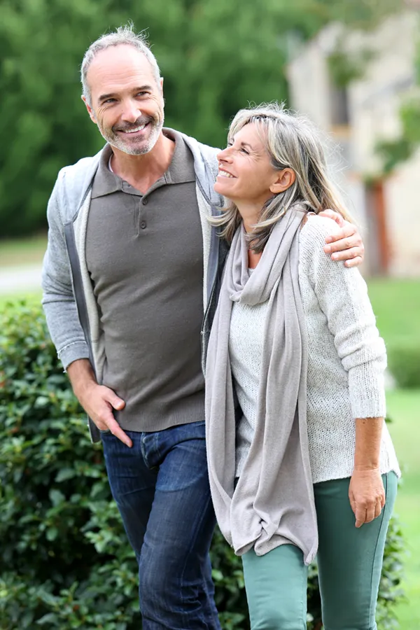 Bioidentical-Hormone-Therapy-Treatment A mature couple in gray toned clothes and jeans walk happily outside, happy with their successful bioidentical hormone treatments from Jennifer Jose-Cappola, MD in Stamford.
