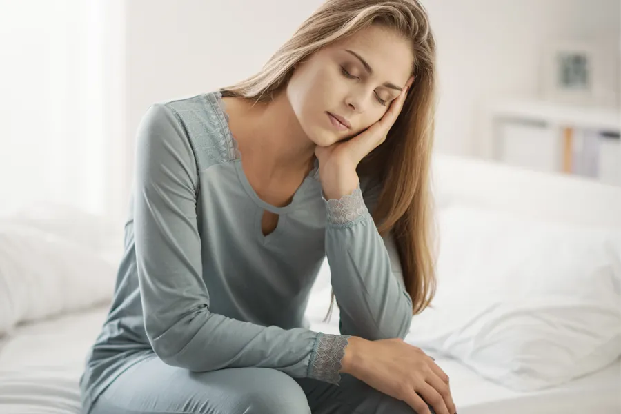 Depression-Clinic A woman sits on the edge of her bed with her head in her hands. Schedule treatment for depression from Jennifer Jose-Cappola, MD in Stamford.