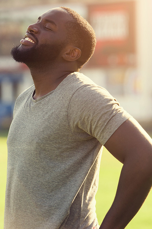 Lean-Muscle-and-Recovery-Treatment A black man in a gray t-shirt and smiles, looking up with closed eyes after a satisfying workout. Get treatment for lean muscle loss and recovery from Jennifer Jose-Cappola, MD in Stamford.