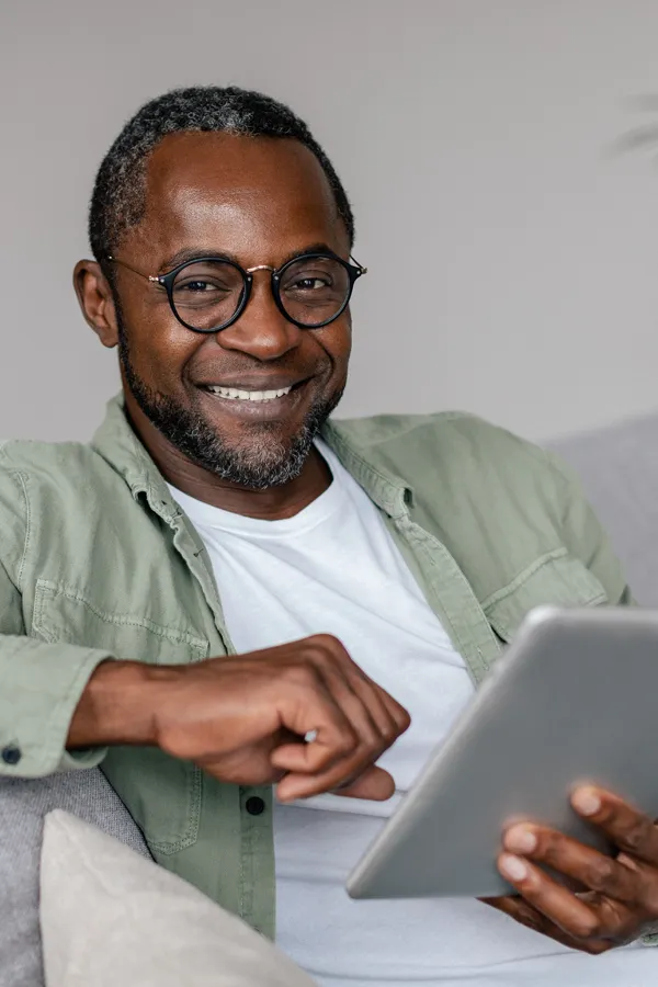 Mood-Imbalance-Treatment A happy Black man using a tablet. Get mood imbalance therapy from Jennifer Jose-Cappola, MD in Stamford.