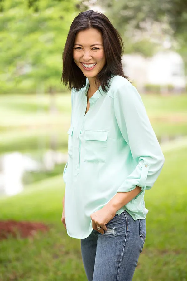 Perimenopause-Treatment A middle-aged brunette woman in a light green button-up shirt stands outside smiling, happy with her perimenopause treatment from Jennifer Jose-Cappola, MD in Stamford.