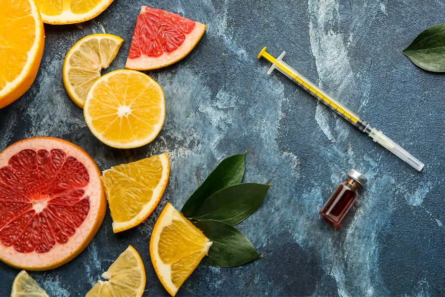 Vitamin-Injection-Doctor A gray marble countertop covered with sliced fruit and a syringe and vial, representing vitamin injections from Jennifer Jose-Cappola, MD in Stamford.